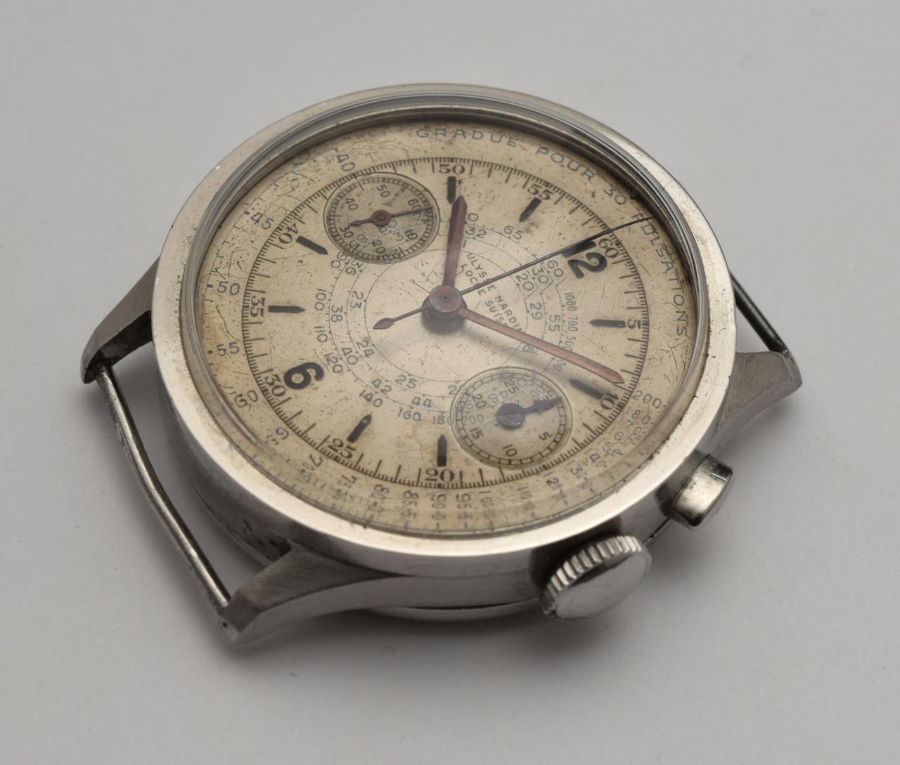 Close-up of an antique chronograph watch with a weathered dial and intricate design.